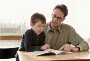 dad and son looking at workbook